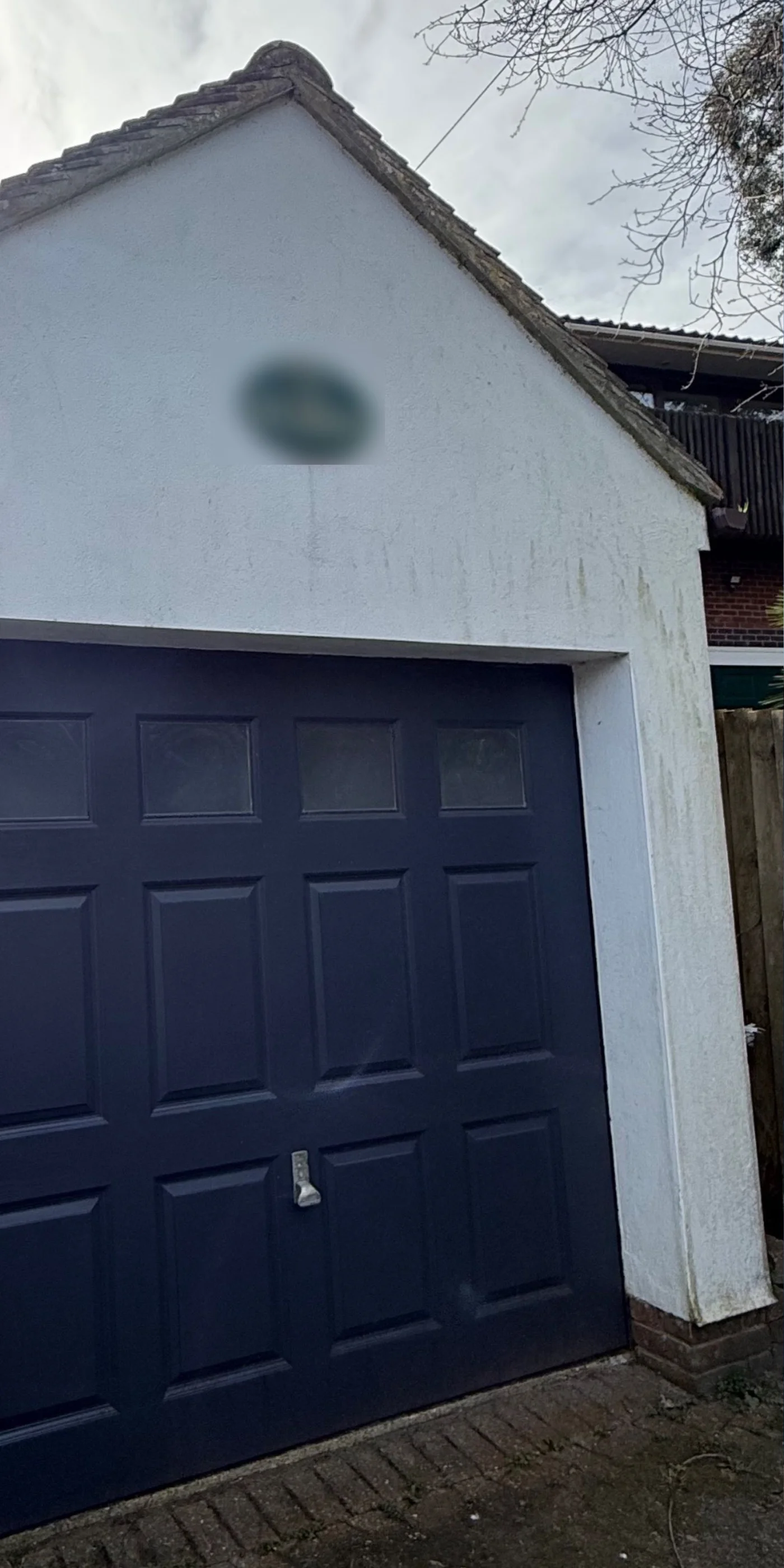 Garage with green-stained render before soft washing