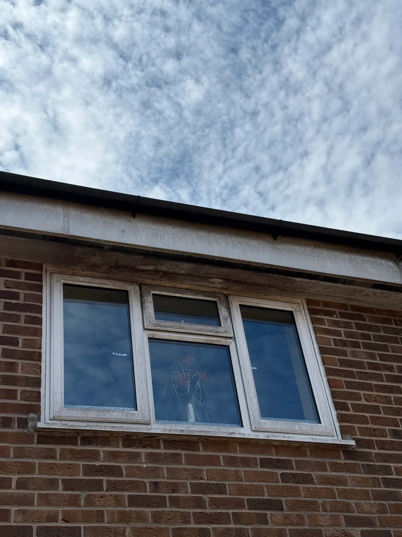 Close-up of a dusty, grime-streaked white uPVC window frame before cleaning