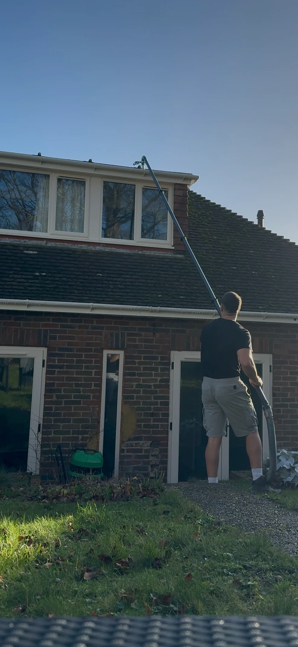 High-reach gutter vacuum pole working on a brick house roofline