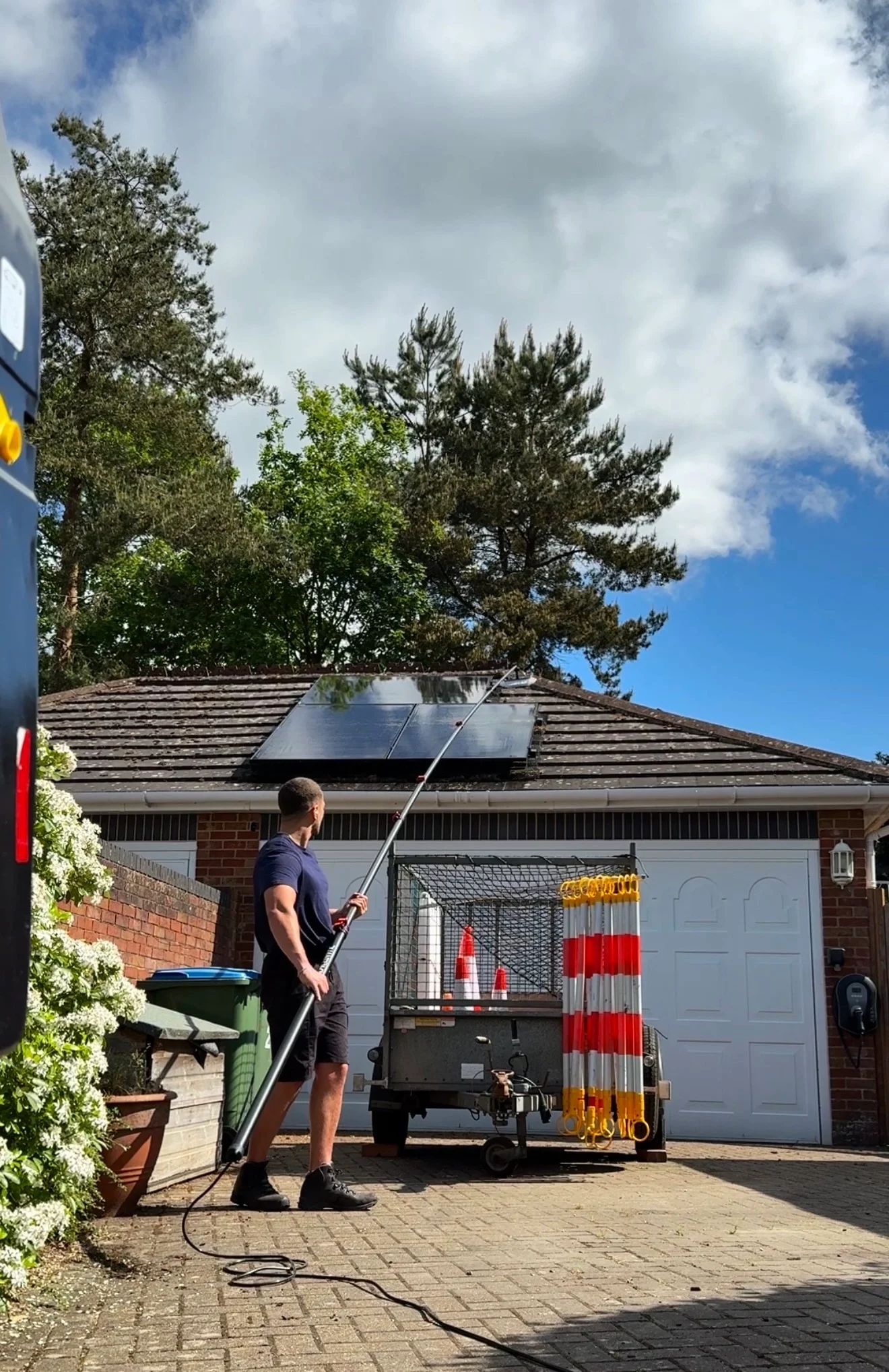 Operative cleaning solar panels on a bungalow garage roof with a water-fed pole